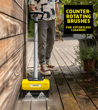 Man cleaning a wooden deck with the Kärcher PCL 6 electric decking cleaner and its counter-rotating brushes