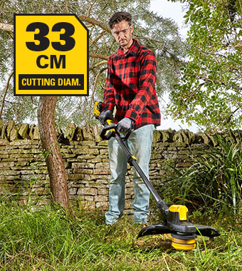 Stanley FatMax V20 SFMCSTB933 – 33 cm Cutting Diameter Stanley FatMax V20 SFMCSTB933 cordless grass trimmer clearing long grass and weeds against a stone wall, with the 33 cm cutting diameter